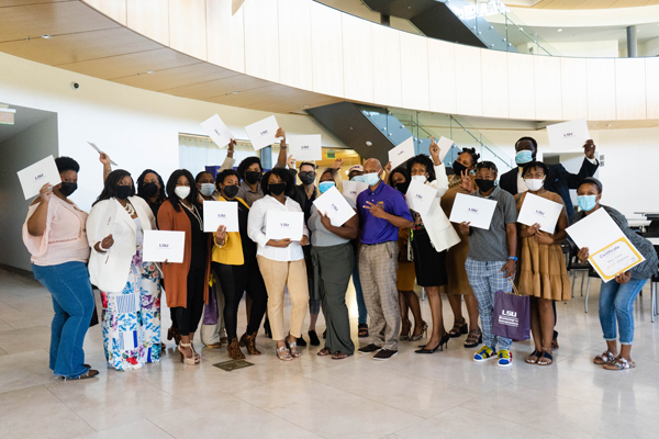 Bootcamp attendees in a group holding their completion certificates.