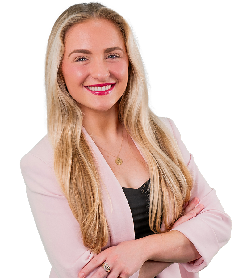 Chloe Chehardy headshot wearing a pink blazer and black shirt. Her arms are crossed.