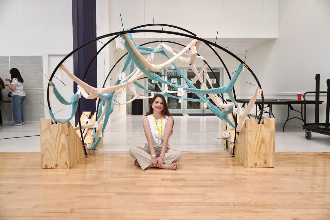 Student posing with an art installation